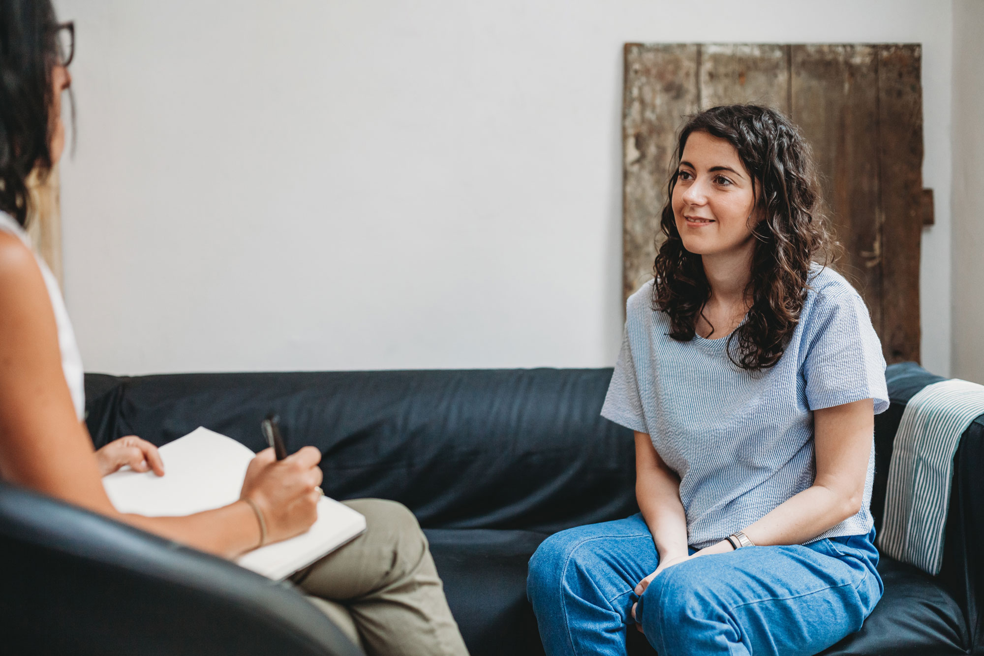 Woman smiling during a therapy session on a couch.